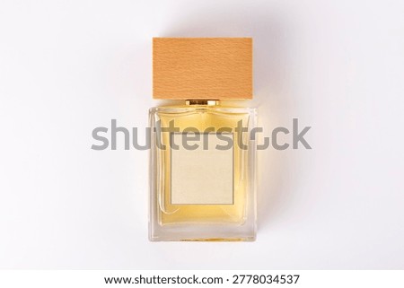 Rectangular glass perfume bottle with blank label and wooden cap, filled with yellow liquid, standing on a white background