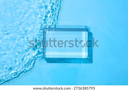 Rectangular glass podium resting in clear water with gentle movement. Structured composition with open space for product, text, or graphic overlay