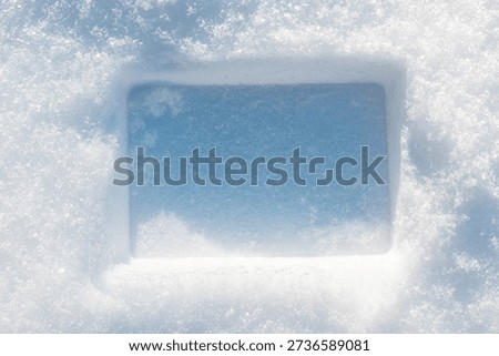 Rectangular imprint on the fluffy, snowy surface with sunlight.