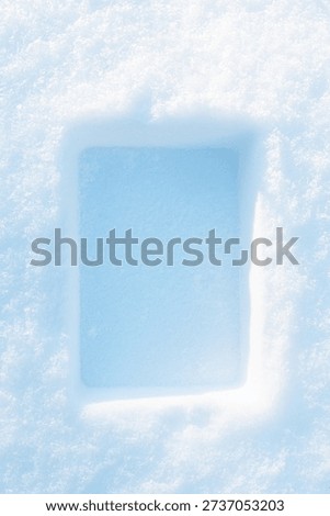 Rectangular imprint on the fluffy, snowy surface with sunlight.