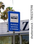 A rectangular metal bus stop sign with a blue reflective surface for complimentary hotel bus services in Albuferia Portugal