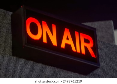 A rectangular "ON AIR" sign illuminates the recording studio. The bright red lettering stands out against the black background.