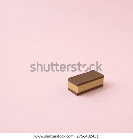A rectangular piece of chocolate on a pink background. The composition is simple, entirely focused on the piece of chocolate.