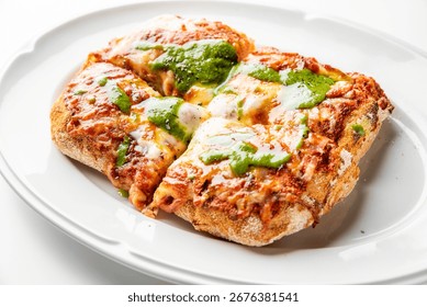 Rectangular pizza with thick rustic crust, melted cheese, tomato sauce, and green pesto, served on a white plate. Top-down view, gourmet style, vibrant colors
