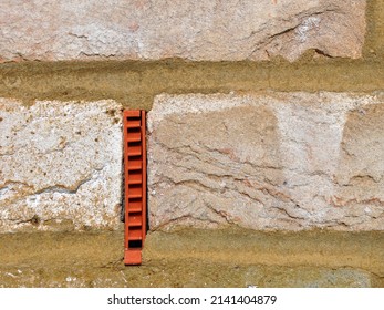 Rectangular plastic Weep vent set in an exterior brick wall. Provides ventilation and drainage for a cavity brick wall. House building construction technique and design element. Day outside
