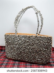 Rectangular shape lady purse decorated with lots of metal accessories (beads having shapes of barrels, watches, butterflies).