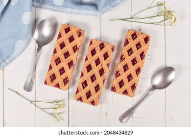Rectangular slices of pie called 'Linzer Torte', a traditional Austrian shortcake pastry topped with fruit preserves and sliced nuts with lattice design 