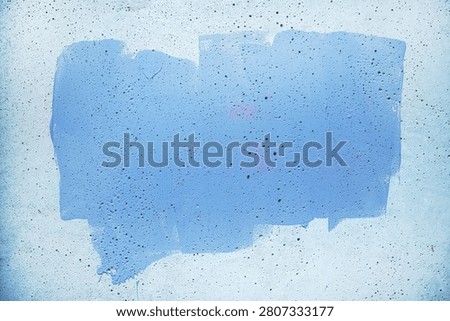 A rectangular swath of blue paint on a rough concrete wall, showing drips, speckled flecks and subtle gradients that form an abstract, grunge-style background ideal for design and editorial use.