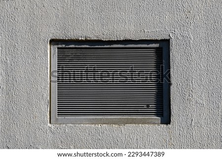 Rectangular ventilation grill in a gray concrete wall
