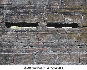 rectangular ventilation holes in a red brick wall of an old house, the house has been demolished and all that remains is the wall
