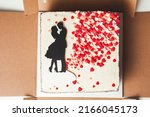 rectangular wedding cake with red hearts scattering and illustration of a loving couple on the white cream cheese frosting