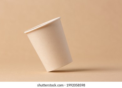 Recyclable cardboard cup balancing on a kraft cardboard background