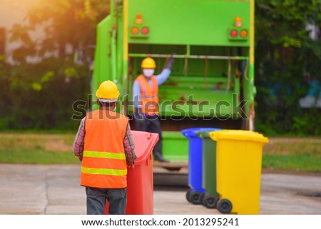 Recyclable garbage truck and the keeper in the village on during sunset.Garbage collector on the garbage truck.Selective focus