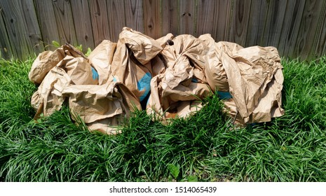 Recyclable Yard Waste Paper Bags On Green Lawn Against Wood Fence.