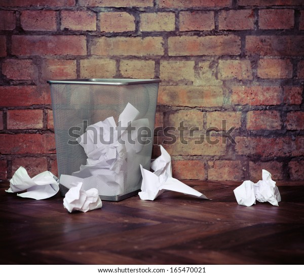 Recycle bin filled with crumpled papers. Brick wall\
background. Retro style