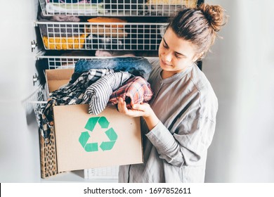Recycle clothes concept. Young woman with recycling box full clothes. - Shutterstock ID 1697852611