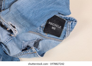 Recycle me, blue jeans with a clothing tag. Circular economy principle, zero waste concept. Reusing materials and reducing waste in fashion. Denim trousers, horizontal shot 