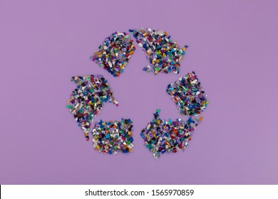 Recycle Symbol Consisting Of Small Plastic Pellets Collected From The Sea Water. Rethinking The Environment By Reducing Or Reusing Plastics. Circular Economy Concept. Lilac Purple Background