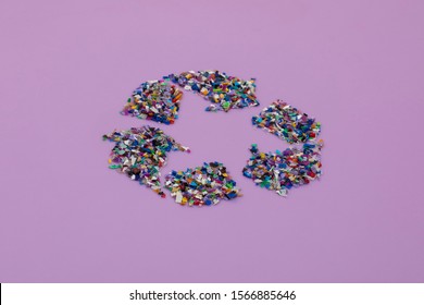 Recycle Symbol Consisting Of Small Plastic Pellets Collected From The Ocean. Rethinking The Environment By Reducing Or Reusing Plastics. Circular Economy Concept. Lilac Purple Background