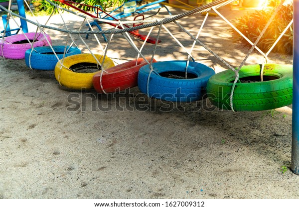 Recycle\
tires wheel on sand ground, paint the color used bridge with rope\
for children or kids walk and balance body to play at\
playground.Concept create value from the\
waste.