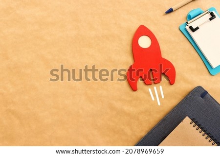 Recycled paper background with officesupplies and wooden rocket