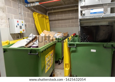 recycling bins and garbage chute disposal room in apartment buil