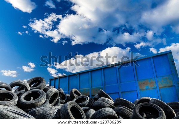 Recycling business with metal container and\
car tires over blue sky. Ecology and recycle industry, saving\
nature and\
environment.