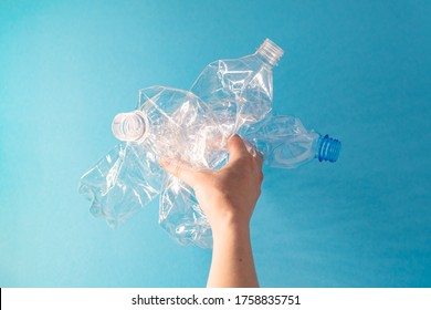 Recycling concept. Female hand holds a rumpled plastic bottles. Ecological problem, top view, blue background. - Shutterstock ID 1758835751