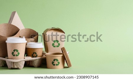 Recycling concept. A set of disposable paper tableware with a recycling sign on a green background. copy space