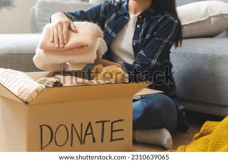 Recycling, Donation for poor, asian young woman, girl sitting pack object at home, putting on stuff into donate box with second hand clothes, charity helping and needy people. Reuse recycle, moving.