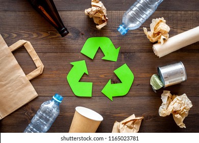 Recycling. Green recycle eco symbol. Recycled arrows sign near matherials for recycle and reuse on dark wooden background top view - Shutterstock ID 1165023781