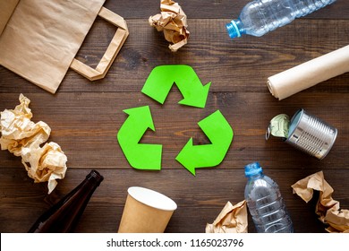 Recycling. Green recycle eco symbol. Recycled arrows sign near matherials for recycle and reuse on dark wooden background top view - Shutterstock ID 1165023796