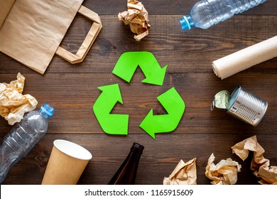 Recycling. Green recycle eco symbol. Recycled arrows sign near matherials for recycle and reuse on dark wooden background top view - Shutterstock ID 1165915609