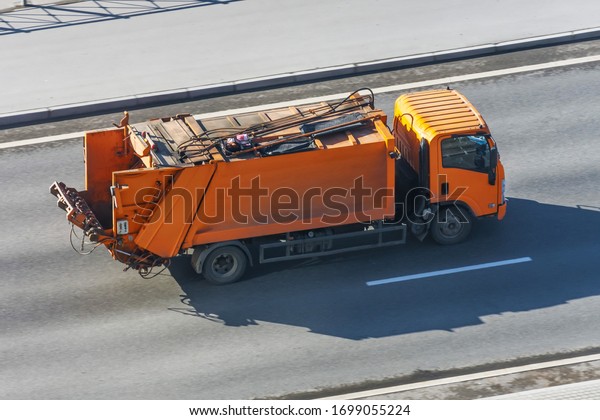 Recycling\
orange truck rides on the road in the\
city