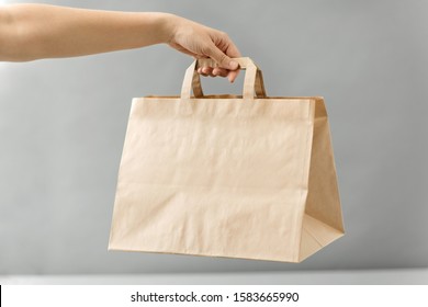 Recycling, Shopping And Ecology Concept - Hand Holding Disposable Brown Takeaway Food In Paper Bag With Lunch On Table