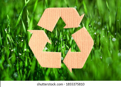Recycling sign made of cardboard on background of green grass with dew. Reuse, reduce, recycle and eco concept.  - Shutterstock ID 1855375810
