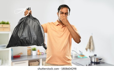 Recycling, Sorting And Sustainability Concept - Young Indian Man Holding Stinky Trash Bag Over Home Kitchen Background