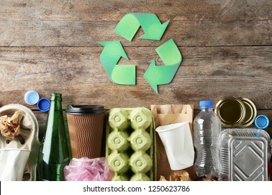 Recycling symbol and different garbage on wooden background, top view - Shutterstock ID 1250623786