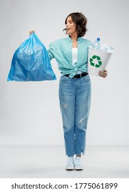 Recycling, Waste Sorting And Sustainability Concept - Smiling Young Woman In Striped T-shirt Holding Rubbish Bin With Plastic Bottles And Trash Bag Over Grey Background