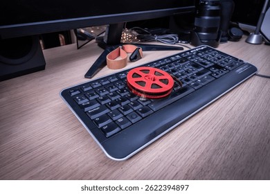 Red 8mm film reel placed on a retro computer keyboard, symbolizing the digitization of analog film in the modern era