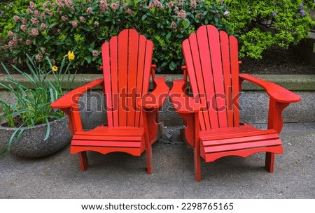 Red Adirondack chair setting at the garden. Traditional curveback red wooden beach chair, outdoor patio adirondack chairs with contoured backs