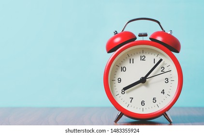 Red alarm clock with 8 O'clock on wooden table and blue background, retro style color.

