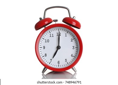 Red alarm clock isolated on white background shows seven o clock in the morning time to get up to wake up and have breakfast morning or evening run to go to work 7 am pm.
