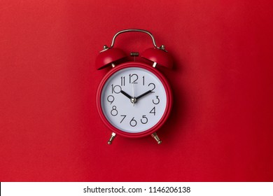 red alarm clock on red background. close up shot. top view.