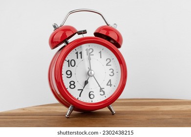 Red alarm clock on grey wall background - Shutterstock ID 2302438215