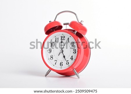 Red alarm clock set at five o'clock isolated on white background. Close-up with clipping path