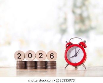 Red alarm clock, Wooden blocks with the number 2026 on stack of coins. The concept of saving money for manage time to success business in year 2026