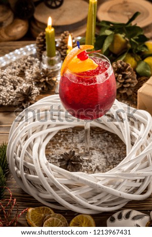 Red Alcoholic Cocktail with ice, orange and cherry on wooden table on christmas decorated background. Studio shot