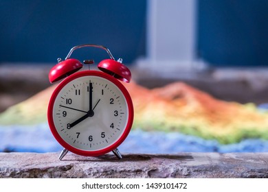 Red Analog Clock On Cement Flor In A House With Snad Colorful And Show Time 8.00 A.m