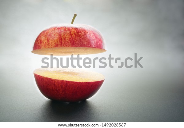 Red apple cut in\
half lit by a ray of light